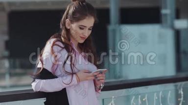 年轻漂亮的<strong>深色</strong>头发，心情很好的粉红色衬衫在<strong>购物</strong>中心。 那个女孩正在发短信。
